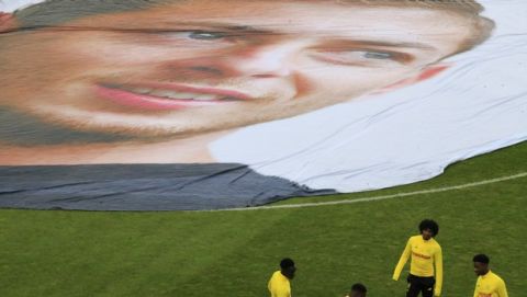 Nantes players warm up next to a giant canvas showing late Argentinian player Emiliano Sala is pictured in La Beaujoire stadium prior the French League One soccer match between Nantes against Bordeaux in Nantes, western France, Sunday, Jan. 26, 2020. Nantes paid an emotional tribute to Emiliano Sala by wearing a special blue and white shirt representing the Argentina team's colors during its home game against Bordeaux. Sala died after the single-engine aircraft carrying him from Nantes to his new club Cardiff crashed near the Channel Island of Guernsey on Jan. 21 last year. (AP Photo/Michel Euler)