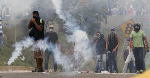 Opponents of President Nicolas Maduro stand amidst tear gas during clashes with security forces in Caracas, Venezuela, Thursday, April 20, 2017. Tens of thousands of protesters flooded the streets again Thursday, one day after three people were killed and hundreds arrested in the biggest anti-government demonstrations in years. (AP Photo/Ariana Cubillos)