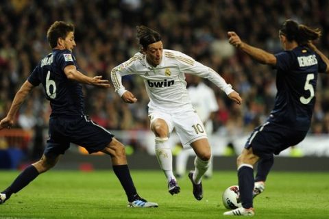 Real Madrid's German midfielder Mesut Ozil (C) vies with Malaga's Argentinian defender Martin Demichelis (R) and Malaga's midfielder Ignacio Camacho (L) during the Spanish league football match Real Madrid vs Malaga at the Santiago Barnabeu stadium in Madrid on March 18, 2012.   AFP PHOTO/JAVIER SORIANO. (Photo credit should read JAVIER SORIANO/AFP/Getty Images)