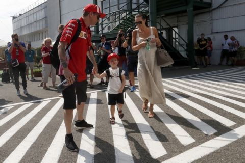 CORRECTS DATE  Ferrari driver Kimi Raikkonen of Finland, left, walks through the paddock with his son Robin and wife Minttu Virtanen prior to the third free practice session for the Hungarian Formula One Grand Prix, at the Hungaroring racetrack in Mogyorod, northeast of Budapest, Saturday, July 28, 2018. The Hungarian Grand Prix will be held on Sunday. (AP Photo/Laszlo Balogh)