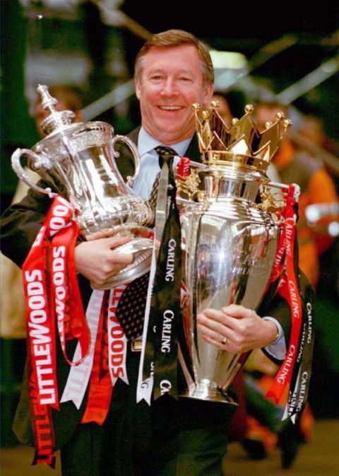 Manchester United manager Alex Ferguson proudly displays the FA Cup (left) and the Carling Premiership trophies as he arrives at Manchester's Victoria Station.