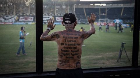 TO GO WITH AFP STORY by Javier Tovar
Brazilian football club Botafogo fan Delneri Martins Viana, a 69-year-old retired soldier, looks at the team's players warming up before a match at Sao Genario stadium in Rio de Janeiro, Brazil, on January 21, 2014. Delneri has 83 tattoos on his body dedicated to Botafogo and describes himself as the club's biggest fan.   AFP PHOTO / YASUYOSHI CHIBA