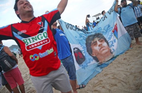 RIO DE JANEIRO, BRAZIL - JULY 11:  Argentine fans sing on Copacabana Beach with a flag of Diego Maradone ahead of the 2014 FIFA World Cup final match against Germany on July 11, 2014 in Rio de Janeiro, Brazil. Up to 100,000 Argentine fans are expected to arrive in Rio for the final match which will be held at the famed Maracana stadium on July 13. (Photo by Mario Tama/Getty Images)