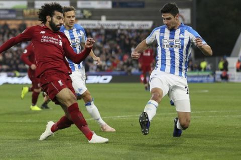 Liverpool's Mohamed Salah, left, scores his side's first goal of the game against Huddersfield Town during their English Premier League soccer match at the John Smith's Stadium in Huddersfield, England, Saturday Oct. 20, 2018. (Richard Sellers/PA via AP)