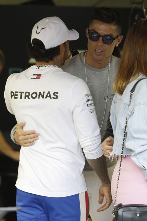 Mercedes driver Lewis Hamilton of Britain, left, speaks with Cristiano Ronaldo at the pit line ahead of the second practice session at the Monaco racetrack, in Monaco, Thursday, May 23, 2019. The Formula one race will be held on Sunday. (AP Photo/Luca Bruno)