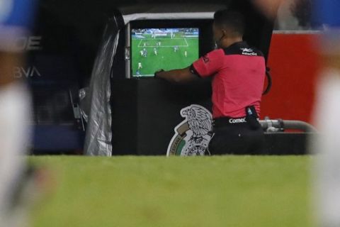 Referee Fernando Guerrero checks the VAR before awarding a penalty kick to America during a Mexican soccer league match against Guadalajara at Azteca stadium in Mexico City, Saturday, Sept. 28, 2019. (AP Photo/Eduardo Verdugo)