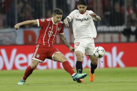 Bayern's James, left, and Sevilla's Ever Banega challenge for the ball during the Champions League quarter final second leg soccer match between FC Bayern Munich and Sevilla FC at the Allianz Arena stadium in Munich, Germany, Wednesday, April 11, 2018. (AP Photo/Matthias Schrader)