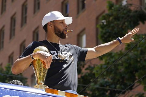 Stephen Curry smokes a cigar and waves while riding in the Golden State Warriors NBA championship parade in San Francisco, Monday, June 20, 2022. (AP Photo/Eric Risberg)
