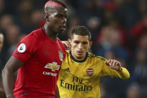 Manchester United's Paul Pogba, left, vies for the ball with Arsenal's Lucas Torreira during the English Premier League soccer match between Manchester United and Arsenal at Old Trafford in Manchester, England, Monday, Sept. 30, 2019. (AP Photo/Dave Thompson)