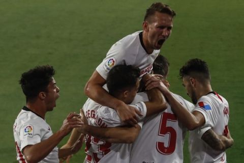 Sevilla's Lucas Ocampos, number 5, is congratulated after scoring against Betis during their Spanish La Liga soccer match in Seville, Spain, Thursday, June 11, 2020. With virtual crowds, daily matches and lots of testing for the coronavirus, soccer is coming back to Spain. The Spanish league resumes this week more than three months after it was suspended because of the pandemic, becoming the second top league to restart in Europe. The Bundesliga was first. The Premier League and the Italian league should be next in the coming weeks. (AP Photo)