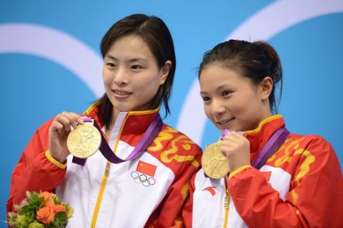China's gold medalists He Zi and Wu Minxia pose on the podium after the women's synchronised 3m springboard diving event at the London 2012 Olympic Games on July 29, 2012 in London.    AFP PHOTO / MARTIN BUREAU        (Photo credit should read MARTIN BUREAU/AFP/GettyImages)