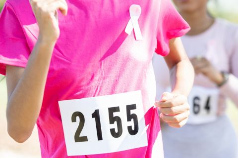 Group of women running marathon in pink, breast cancer awareness ribbon