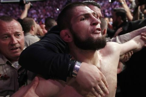 FILE- In this Oct. 6, 2018, file photo, Khabib Nurmagomedov is held back outside of the cage after fighting Conor McGregor in a lightweight title mixed martial arts bout at UFC 229 in Las Vegas. Nurmagomedov was fined $500,000 and suspended for nine months for a brawl inside and outside the octagon after his fight with Conor McGregor at UFC 229. McGregor was fined $50,000 and suspended for six months. The suspensions for both fighters are retroactive to Oct. 6. (AP Photo/John Locher, File)