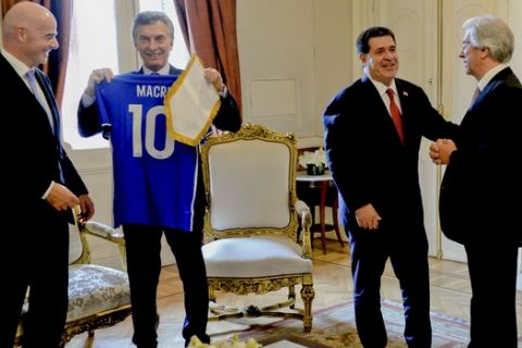 In this photo provided by the Argentine Presidency, Argentina's President Mauricio Macri, second left, looks at a soccer jersey with his name, next to FIFA President Gianni Infantino, left, as Paraguay's President Horacio Cartes, second right, talks to Uruguay's President Tavare Vazquez, right, at Casa Rosada in Buenos Aires, Argentina, Wednesday, Oct. 4, 2017. The three South American countries say they will chase a bid for the 2030 World Cup, which is expected to be competitive with China and Britain possibly in the mix. (Argentine Presidency via AP)