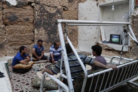 Syrians watch the World Cup soccer final match between France and Croatia at their home, that was partially destroyed by the war leaving two of its rooms without a ceiling, in the town of Ain Terma, in the Eastern Ghouta suburb of Damascus, Syria, Sunday, July 15, 2018. (AP Photo/Hassan Ammar)