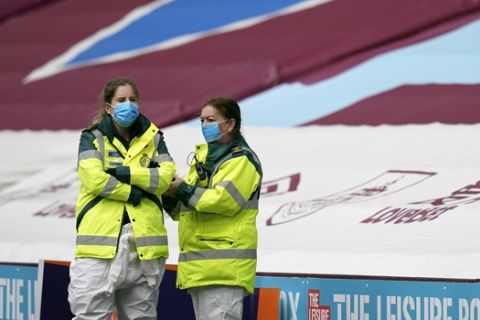 Stewards wearing protective masks wait for the kick-off of the English Premier League soccer match between Burnley and Sheffield United, at Turf Moor Stadium in Burnley, England, Sunday, July 5, 2020. (AP Photo/Jon Super, Pool)