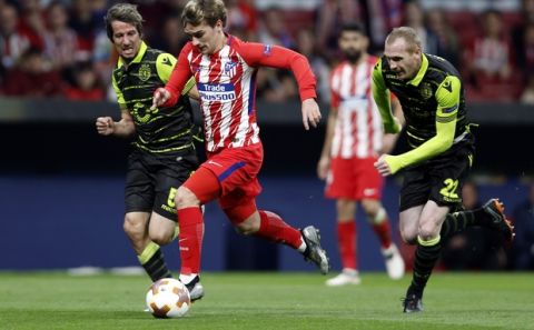 Atletico's Antoine Griezmann, center, escapes Sporting's Jeremy Mathieu, right, to score his side's second goal during the Europa League quarterfinal first leg soccer match between Atletico Madrid and Sporting CP at the Metropolitano stadium in Madrid, Thursday, April 5, 2018. (AP Photo/Francisco Seco)