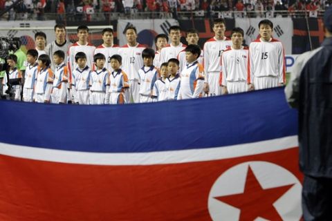 FILE - In this April 1, 2009, file photo, North Korean national soccer team players listen the national anthem in front of their national flag before their 2010 FIFA World Cup Asia group 2 qualifying soccer match against South Korea at Seoul World Cup Stadium in Seoul, South Korea. The South Korean men's national soccer team's path to the 2022 World Cup in Qatar will include a crucial road match against North Korea, but it's unclear whether a rare match between the Koreas in Pyongyang will materialize considering the political tension between the rivals. (AP Photo/ Lee Jin-man, File)