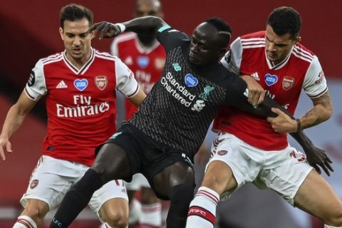 Arsenal's Granit Xhaka, right, grabs Liverpool's Sadio Mane during the English Premier League soccer match between Arsenal and Liverpool at the Emirates Stadium in London, England, Wednesday, July 15, 2020. (Shaun Botterill/Pool via AP)