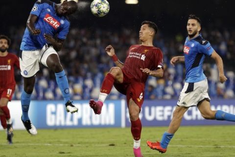 Napoli's Kalidou Koulibaly, left, heads the ball as Liverpool's Roberto Firmino tries to stop him during the Champions League Group E soccer match between Napoli and Liverpool, at the San Paolo stadium in Naples, Italy, Tuesday, Sept. 17, 2019. (AP Photo/Gregorio Borgia)