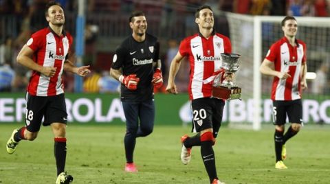 Athletic Bilbao's forward Aritz Aduriz (2nd R) runs with the Supercup trophy next to Athletic Bilbao's midfielder Carlos Gurpegui (L) as they celebrate after the Spanish Supercup second-leg football match FC Barcelona vs Athletic Club Bilbao at the Camp Nou stadium in Barcelona on August 17, 2015. AFP PHOTO / QUIQUE GARCIA        (Photo credit should read QUIQUE GARCIA/AFP/Getty Images)