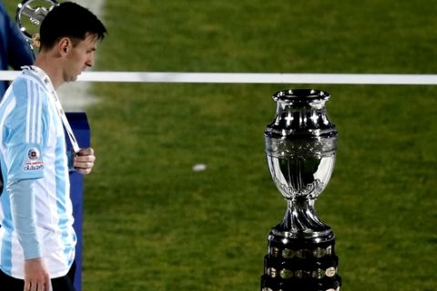 FILE - In this July 4, 2015 file photo, Argentina's Lionel Messi walks next to the Copa America trophy during the Copa America final soccer match at the National Stadium in Santiago, Chile. Messi's shocking decision to stop playing for Argentina could further hurt his already tarnished legacy with his national team. If Messi sticks to his announcement, made in the heat-of-the-moment shortly after Argentina's penalty shootout loss to Chile in Sunday's Copa America final on June 26, 2016, Argentina will be left dwelling on the fact that it was not able to win any significant title while having one of the best players of all time.  (AP Photo/Silvia Izquierdo, File)