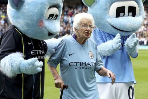 Moonchester and Moonbeam pose for photos with Manchester City Mascot Vera Cohen, during the English Premier League soccer match between Manchester City and Fulham, at the Etihad Stadium, in Manchester, England, Saturday Sept.15, 2018. Manchester City went with an extremely experienced lineup with its mascots for its English Premier League match against Fulham. The roles, which are usually reserved for children, were filled by two of the club's oldest supporters. The Premier League champion was led onto the pitch at Etihad Stadium by Vera Cohen, aged 102, and her sister Olga Halon, 97. (Martin Rickett/PA  via AP)