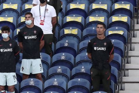 Portugal's Cristiano Ronaldo, right, stands next to the team substitutes on the stands during the UEFA Nations League soccer match between Portugal and Croatia at the Dragao stadium in Porto, Portugal, Saturday, Sept. 5, 2020. Ronaldo is not playing due to an injury. (AP Photo/Miguel Angelo Pereira)