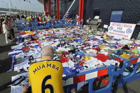 A man looks at tributes to Bolton Wanderers' Fabrice Muamba outside their Reebok stadium ahead of their English Premier League soccer match against Blackburn Rovers in Bolton March 24, 2012. REUTERS/Nigel Roddis (BRITAIN - Tags: SPORT SOCCER) FOR EDITORIAL USE ONLY. NOT FOR SALE FOR MARKETING OR ADVERTISING CAMPAIGNS. NO USE WITH UNAUTHORIZED AUDIO, VIDEO, DATA, FIXTURE LISTS, CLUB/LEAGUE LOGOS OR "LIVE" SERVICES. ONLINE IN-MATCH USE LIMITED TO 45 IMAGES, NO VIDEO EMULATION. NO USE IN BETTING, GAMES OR SINGLE CLUB/LEAGUE/PLAYER PUBLICATIONS