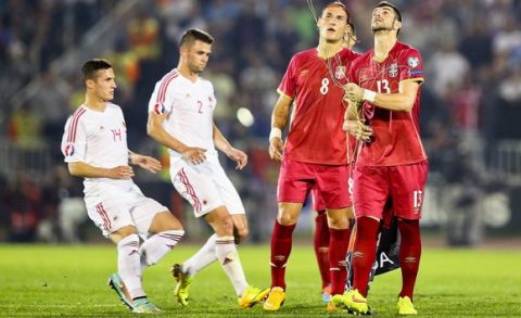 epa04447012 Serbian players try to recover a flag on the pitch before the Euro 2016 Group I qualifying match between Serbia and Albania was suspended, at the Partizan stadium in Belgrade, Serbia, 14 October 2014. The match was suspended after the flag Albanian symbols was flown above the stadium remote controlled by a drone which provoked a fight between players.  EPA/SRDJAN SUKI