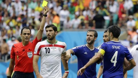 Referee Carlos Velasco Carballo of Spain shows a yellow card to Iran's Karim Ansarifard, second left, during the group F World Cup soccer match between Bosnia and Iran at the Arena Fonte Nova in Salvador, Brazil, Wednesday, June 25, 2014. (AP Photo/Sergei Grits)