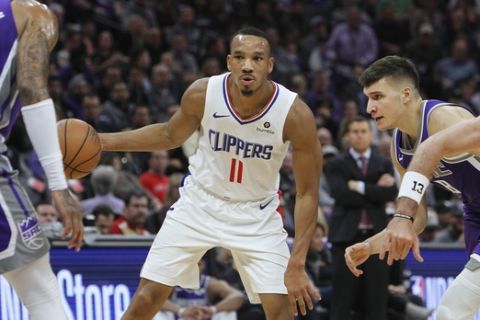Los Angeles Clippers guard Avery Bradley (11) looks for an opening as Sacramento Kings center Willie Cauley-Stein (00) and guard Bogdan Bogdanovic (8) defend during the first half of an NBA basketball game in Sacramento, Calif., Thursday, Nov. 29, 2018. (AP Photo/Steve Yeater)