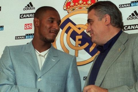 French soccer striker Nicolas Anelka, left, shakes hands with Real Madrid's President Lorenzo Sanz after signing with Real Madrid at the club's Bernabeu Stadium in Madrid Thursday, Aug. 5, 1999. Anelka, formerly of Arsenal, signed a 7 year contract with the Spanish club. (AP Photo/Paul White)