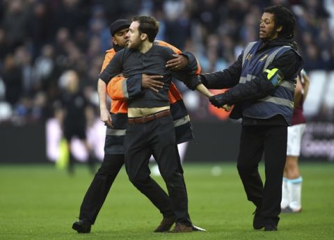 A Pitch invader is seized by security staff during the English Premier League soccer match between Burnley and West Ham at the Olympic London Stadium in London, Saturday, March 10, 2018. (Daniel Hambury/PA via AP)