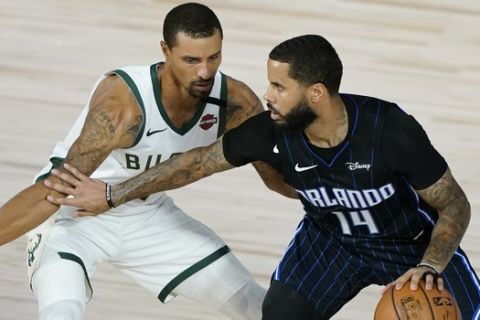 Orlando Magic's D.J. Augustin (14) drives around Milwaukee Bucks' George Hill, left, during the second half of an NBA basketball first round playoff game Monday, Aug. 24, 2020, in Lake Buena Vista, Fla. (AP Photo/Ashley Landis, Pool)
