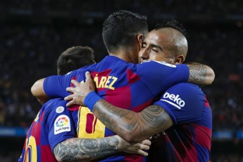 Barcelona's Luis Suarez, center, celebrates with teammates Lionel Messi, left, and Arturo Vidal after scoring the opening goal during Spanish La Liga soccer match between Barcelona and Sevilla at the Camp Nou stadium in Barcelona, Sunday, Oct. 6, 2019. (AP Photo/Joan Monfort)