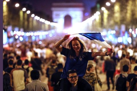People celebrate on the Champs Elysees avenue, with the Arc de Triomphe in background, to celebrate after the semifinal match between France and Belgium at the 2018 soccer World Cup, Tuesday, July 10, 2018 in Paris. France advanced to the World Cup final for the first time since 2006 with a 1-0 win over Belgium on Tuesday. (AP Photo/Jean-Francois Badias)