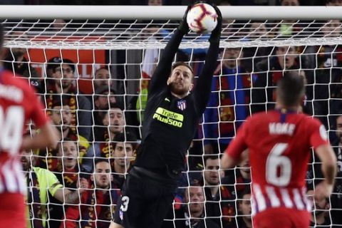 Barcelona forward Lionel Messi fall to the ground, left, and Atletico goalkeeper Jan Oblak saves during a Spanish La Liga soccer match between FC Barcelona and Atletico Madrid at the Camp Nou stadium in Barcelona, Spain, Saturday April 6, 2019. (AP Photo/Manu Fernandez)