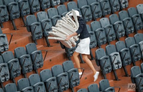 In this Tuesday, June 6, 2017 photo, a hostess removes seat cushion as rain delays the play between France's Kristina Mladenovic and Timea Bacsinszky of Switzerland during their quarterfinal match of the French Open tennis tournament at the Roland Garros stadium in Paris. (AP Photo/Michel Euler)
