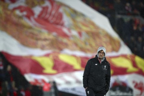Liverpool's manager Juergen Klopp walks in front of a large flag through the rain ahead of the English Premier League soccer match between Liverpool and Chelsea at Anfield stadium in Liverpool, England, Tuesday, Jan. 31, 2017. (AP Photo/Dave Thompson)