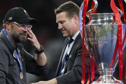 Liverpool coach Juergen Klopp, left looks at the trophy after collecting his winners medal after the Champions League final soccer match between Tottenham Hotspur and Liverpool at the Wanda Metropolitano Stadium in Madrid, Saturday, June 1, 2019. (AP Photo/Bernat Armangue)
