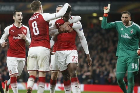 Arsenal's Danny Welbeck celebrates with his teammate Aaron Ramsey, left, after scoring his side opening goal on a penalty, as AC Milan goalkeeper Gianluigi Donnarumma gestures, during the Europa League round of 16 second leg soccer match between Arsenal and AC Milan at the Emirates stadium in London, Thursday, March, 15, 2018. (AP Photo/Alastair Grant)