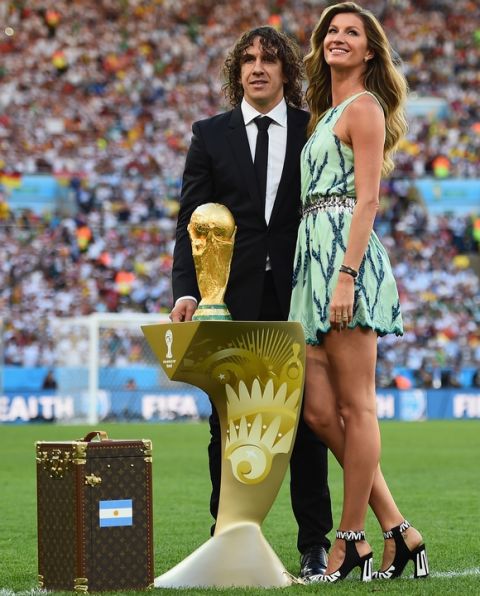 RIO DE JANEIRO, BRAZIL - JULY 13:  Former Spanish international Carles Puyol and model Gisele Bundchen present the World Cup trophy in a Louis Vuitton case prior to the 2014 FIFA World Cup Brazil Final match between Germany and Argentina at Maracana on July 13, 2014 in Rio de Janeiro, Brazil.  (Photo by Laurence Griffiths/Getty Images)