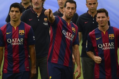FC Barcelona's Luis Suarez, from Uruguay, left, looks on near of Barcelona's Sergio Busquets, second left, and Lionel Messi, from Argentina, during his official presentation prior of the Joan Gamper trophy match Between FC Barcelona and Leon at the Camp Nou in Barcelona, Spain, Monday, Aug. 18, 2014. (AP Photo/Manu Fernandez)