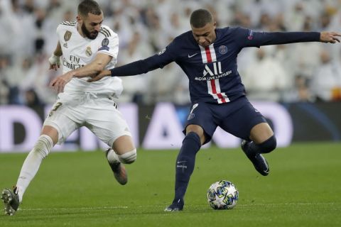 Real Madrid's Karim Benzema fights for the ball against PSG's Kylian Mbappe during a Champions League soccer match Group A between Real Madrid and Paris Saint Germain at the Santiago Bernabeu stadium in Madrid, Spain, Tuesday, Nov. 26, 2019. (AP Photo/Bernat Armangue)