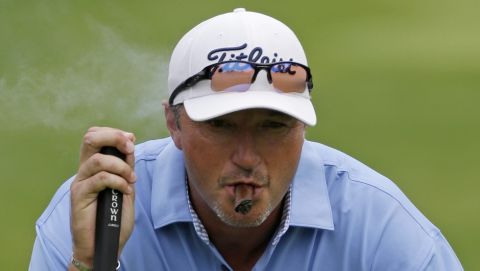 Former NBA basketball player Toni Kukoc, of Croatia, smokes a cigar as he reads his putt on the seventh green during the first round of the Encompass Championship golf tournament on Friday, June 21, 2013, in Glenview, Ill. (AP Photo/Nam Y. Huh)