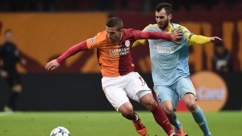 Galatasaray's German forward Lukas Podolski (L) vie for the ball with Astana's Bosnian defender Marin Anicic  during the UEFA Champions League Group C football match between Galatasaray AS and FC Astana at the Turk Telekom Arena in Istanbul on December 8, 2015. AFP PHOTO / OZAN KOSE / AFP / OZAN KOSE        (Photo credit should read OZAN KOSE/AFP/Getty Images)