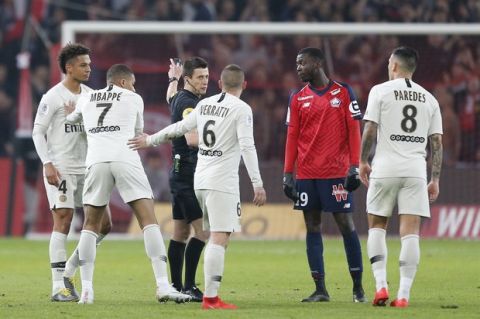 PSG players Thilo Kehrer, Kylian Mbappe and Marco Verratti, from left, talk with referee Benoit Bastien during the French League One soccer match between OSC Lille and Paris-Saint-Germain at Stade Pierre Mauroy in Lille, France, Sunday, April 14, 2019.(AP Photo/Michel Spingler)