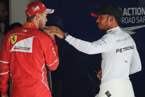 Mercedes driver Lewis Hamilton of Britain, right, talks to Ferrari driver Sebastian Vettel of Germany after taking pole position for the Chinese Formula One Grand Prix at the Shanghai International Circuit in Shanghai, China, Saturday, April 8, 2017. Vettel was second. (AP Photo/Andy Wong)