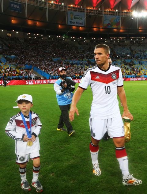 RIO DE JANEIRO, BRAZIL - JULY 13:  Lukas Podolski of Germany walks on the field with his son Louis Podolski after defeating Argentina 1-0 in extra time during the 2014 FIFA World Cup Brazil Final match between Germany and Argentina at Maracana on July 13, 2014 in Rio de Janeiro, Brazil.  (Photo by Martin Rose/Getty Images)